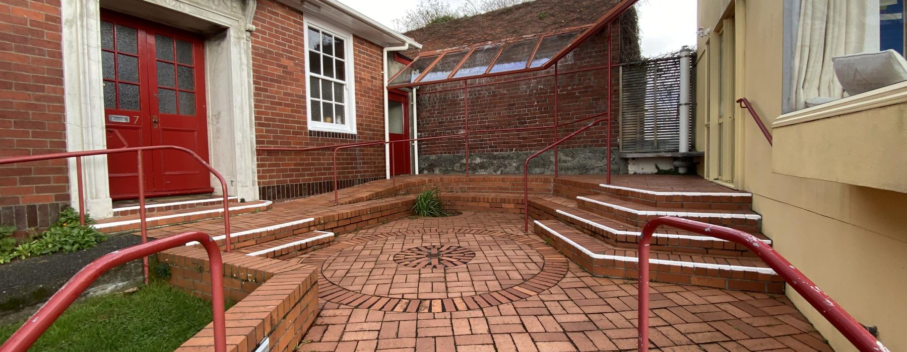 A brick courtyard between two buildings. The left building says "Friends House" over the door.